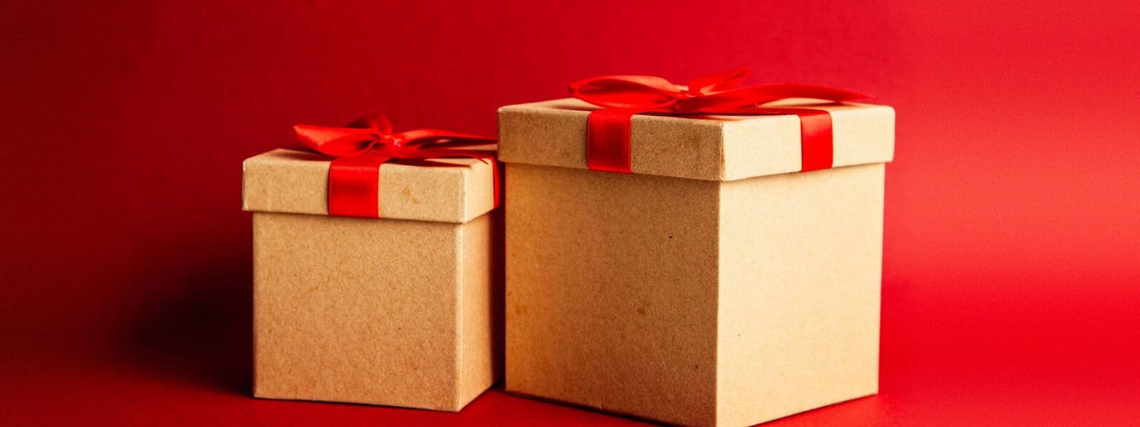 Hai hộp giấy kraft buộc ruy băng đỏ trên nền đỏ